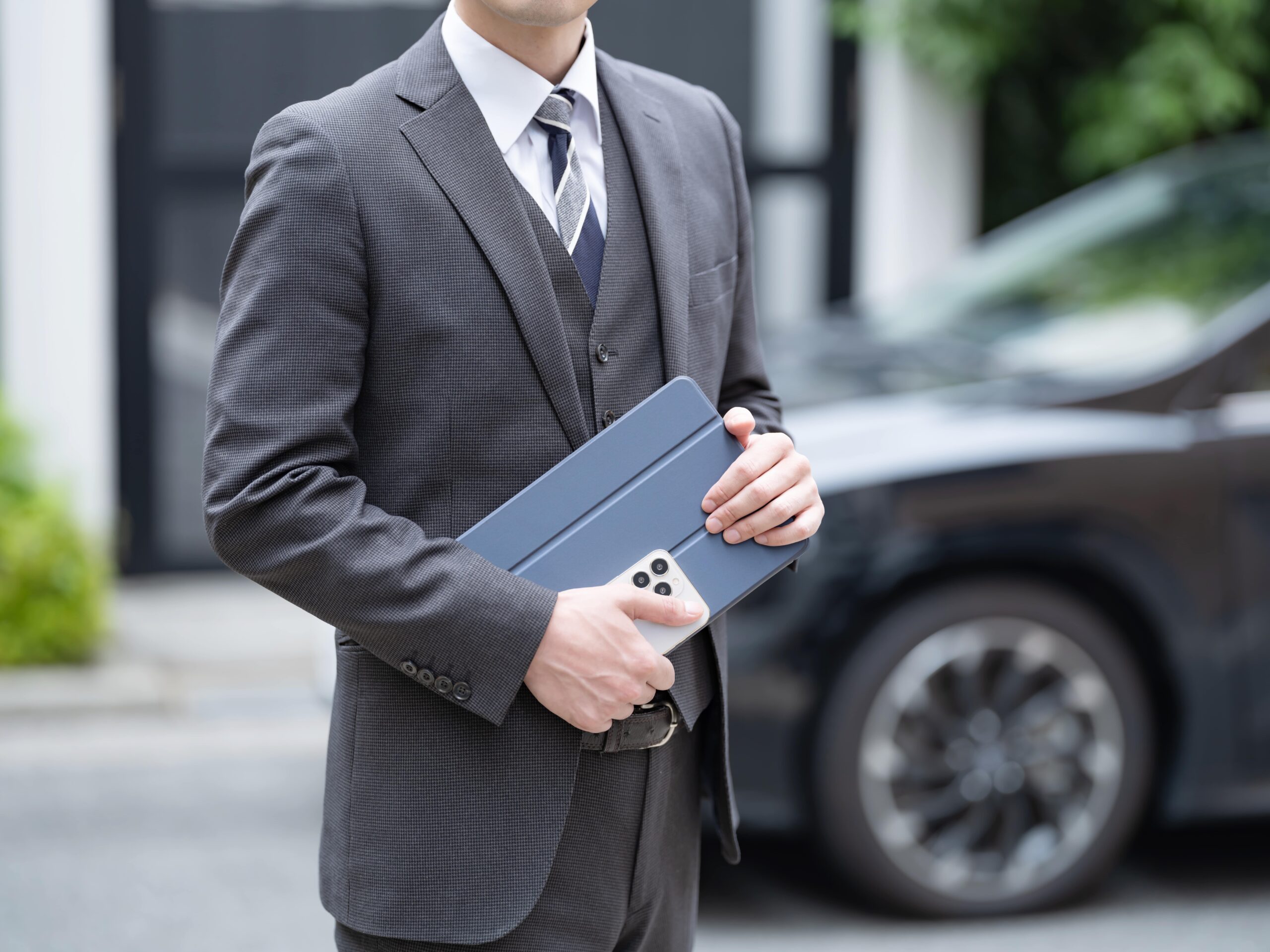車のそばで資料を持つ男性